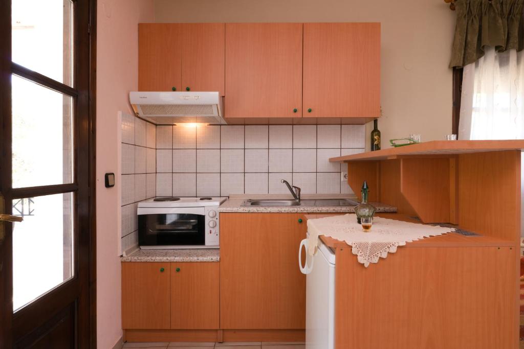 eine Küche mit Holzschränken und einer weißen Mikrowelle in der Unterkunft Anastasia Apartments in Skala Potamias
