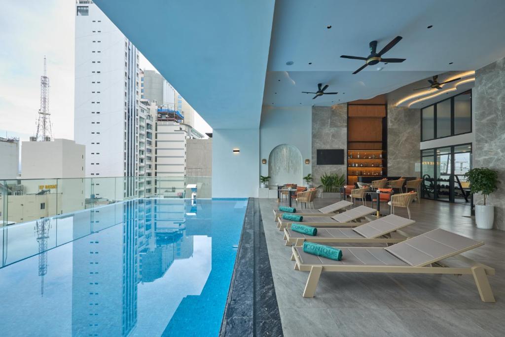 a pool with chaise lounges and chairs in a building at Iconique Hotel Nha Trang in Nha Trang