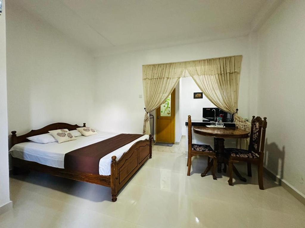 a bedroom with a bed and a desk and a table at Kandyan Gate Homestay in Kandy