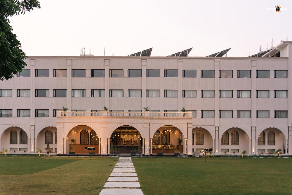 a large white building with a lawn in front of it at Hotel Aamodh in Lucknow