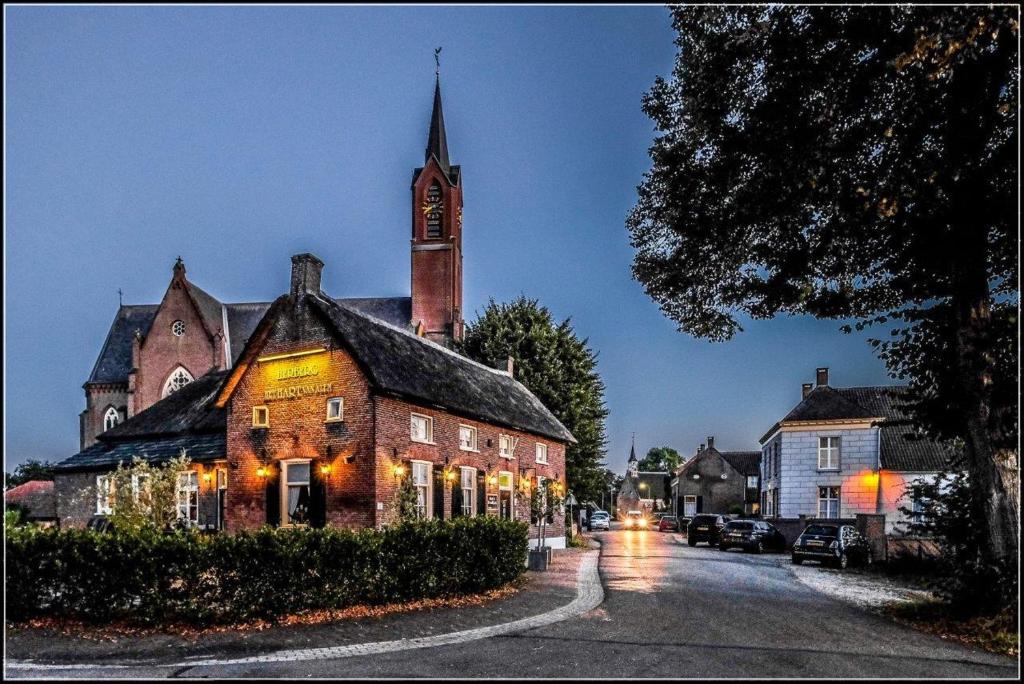 een oud gebouw met een klokkentoren op een straat bij Het Hart Van Alem in Alem