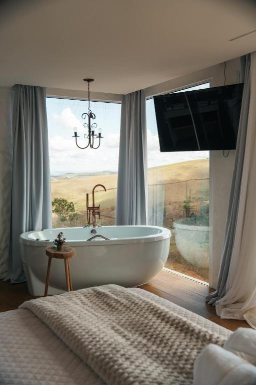 a bathroom with a tub and a window with a view at Cabana Greece house blue in Paty do Alferes