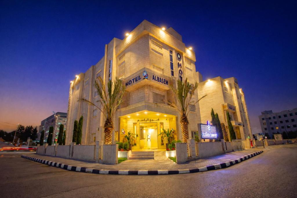 un grande edificio con palme di fronte di Al Basem Hotel ad Amman