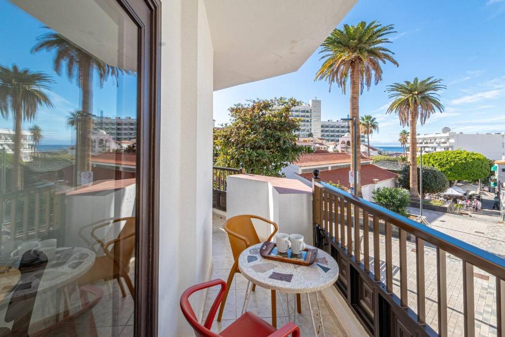 a balcony with a table and chairs and palm trees at El Nido Apartment in Acantilado de los Gigantes
