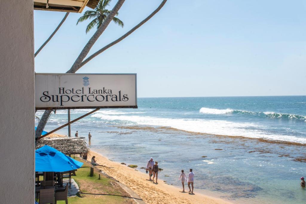 people walking on the beach near the ocean at Hotel Lanka Super Corals in Hikkaduwa