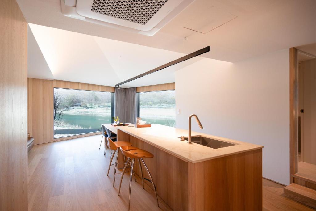 a kitchen with a sink and a counter with stools at 롯지호텔 디여라 in Andong