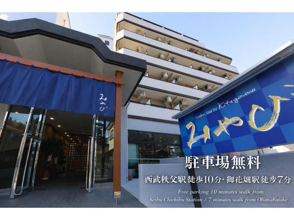 a building with a blue sign in front of it at Comfort stay Miyabi in Chichibu