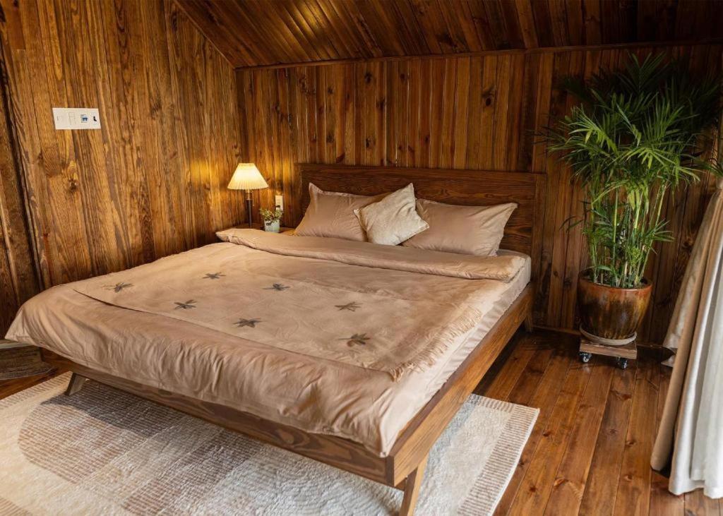 a bedroom with a large bed with wooden walls at Trại Mít Farm in Sóc Sơn