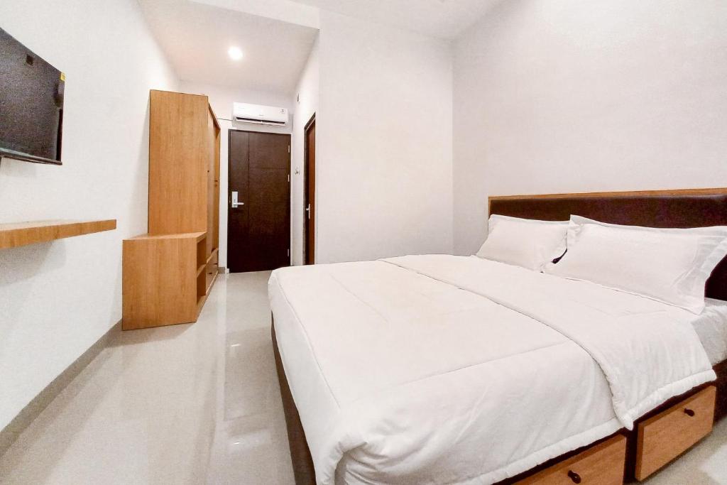 a bedroom with a large white bed and a door at Sans Vibes Viandara Pekanbaru in Parit