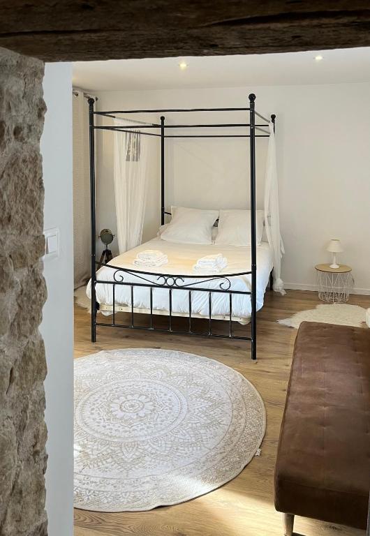 a bedroom with a black canopy bed with a rug at Studio Privatif - Ancienne Maison Vigneronne in Châtel-Guyon
