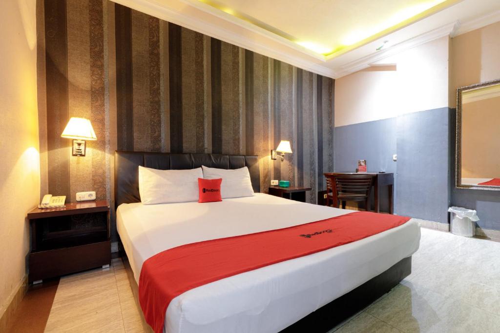 a bedroom with a large bed with a red blanket at RedDoorz Plus near Simpang Tiga Tritayasa Cilegon in Cilegon