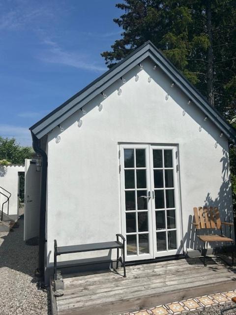 a small white building with a bench in front of it at Cosy guesthouse close to cities in Hjärup