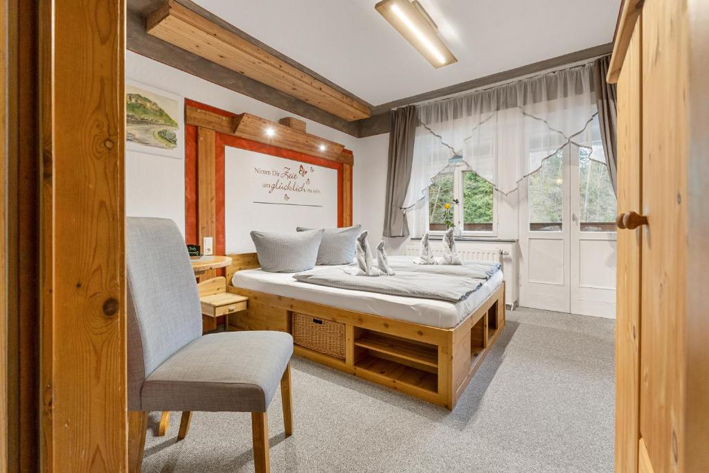 a bedroom with a bed and a chair and a window at Pension Schrammsteinbaude in Bad Schandau
