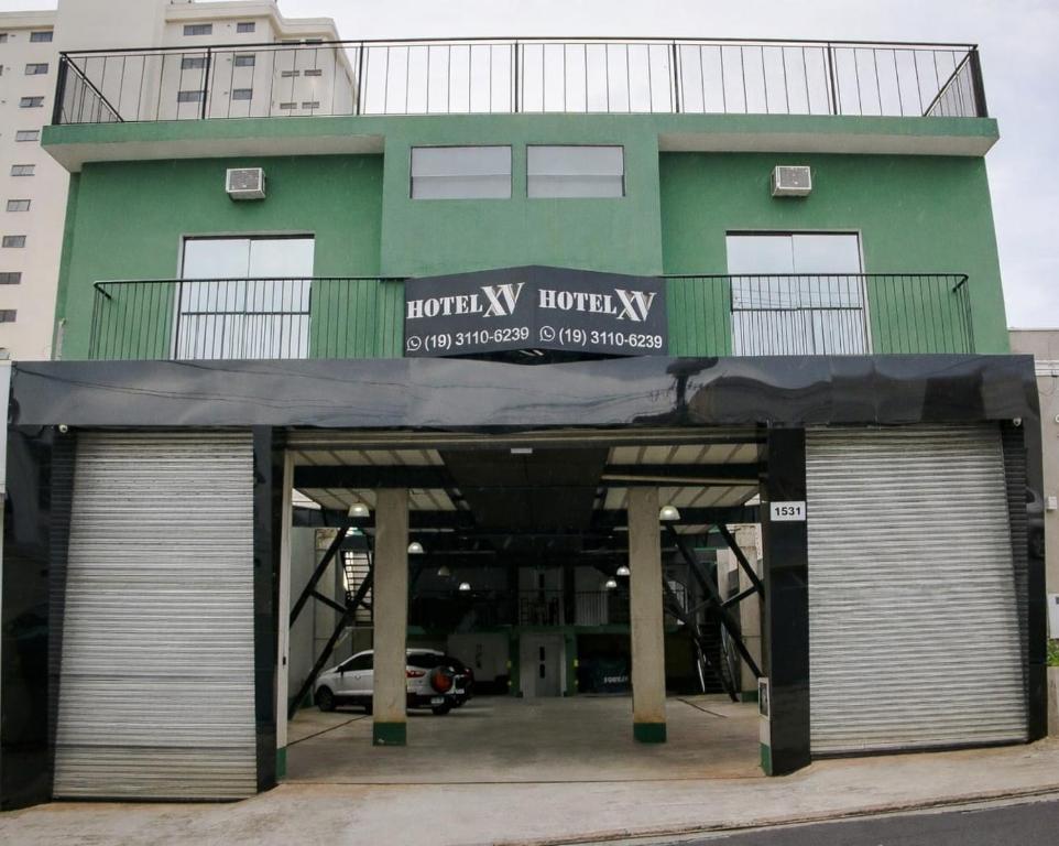 a green building with two garage doors in front of it at Hotel XV in Piracicaba