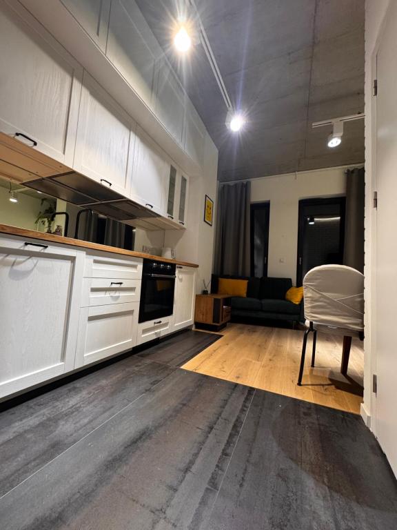 a kitchen with white cabinets and a table and a chair at Apartament Centrum 19 in Nowy Sącz