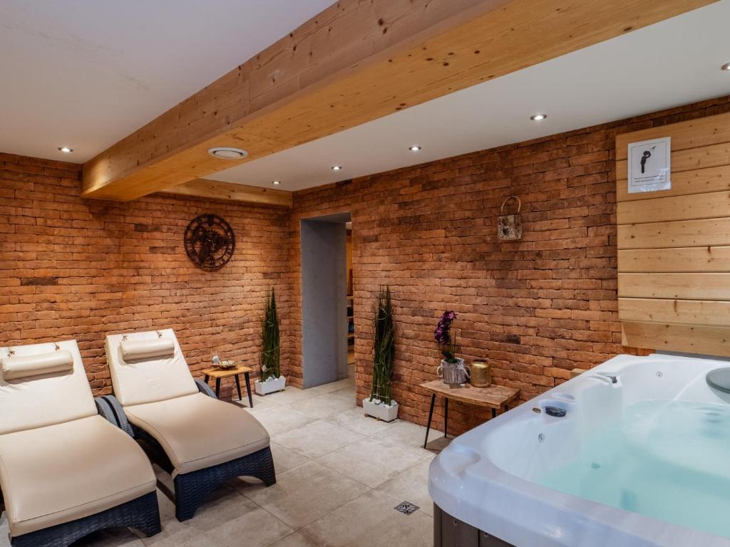 a bathroom with a tub and a brick wall at Villa Jarosta Premium & SPA in Zakopane