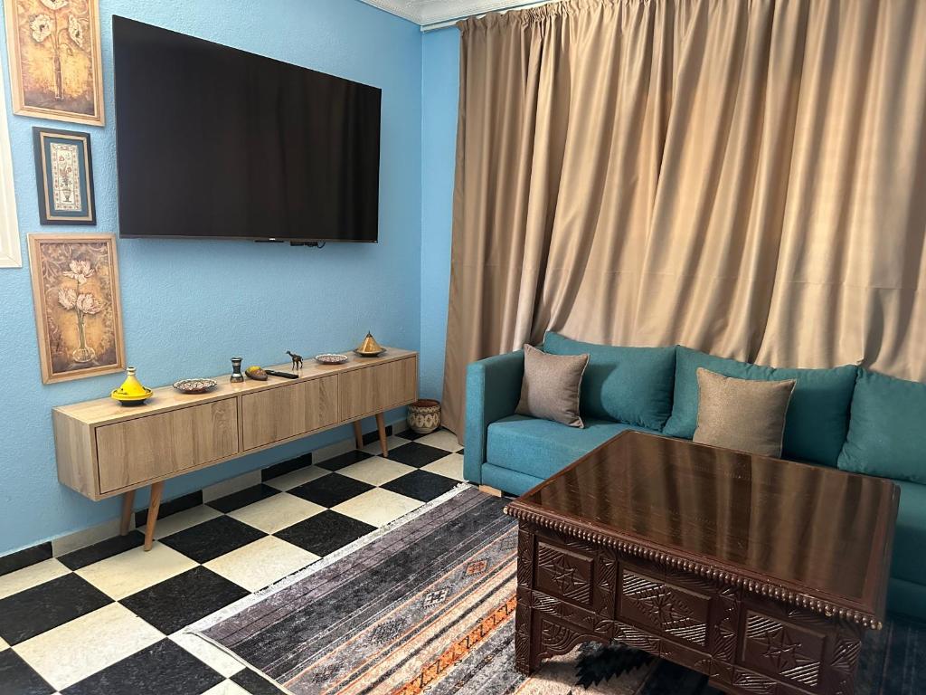 a living room with a blue couch and a tv at Amazing apartment with traditional touch in Taskala