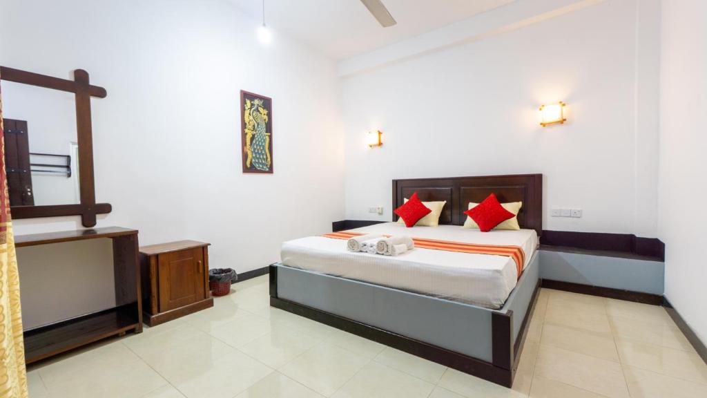 a bedroom with a bed with red pillows at Pearl Guest House in Dambulla