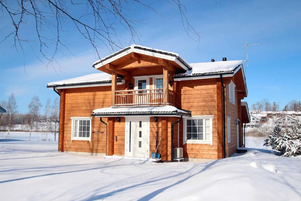 a wooden house with a balcony in the snow at Villa Lily ski slopes 300 m, Jacuzzi for extra fee in Himos