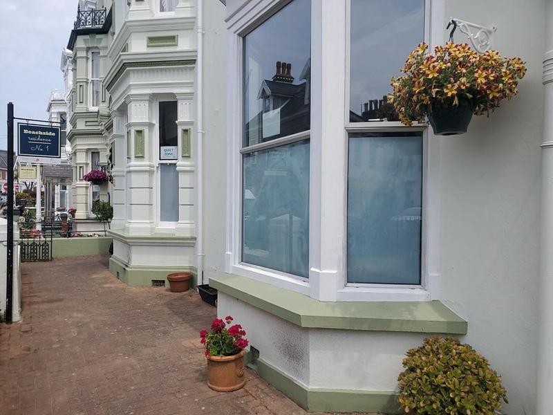 a building with two windows and potted plants on it at Beachside 1 in Saint Helier Jersey