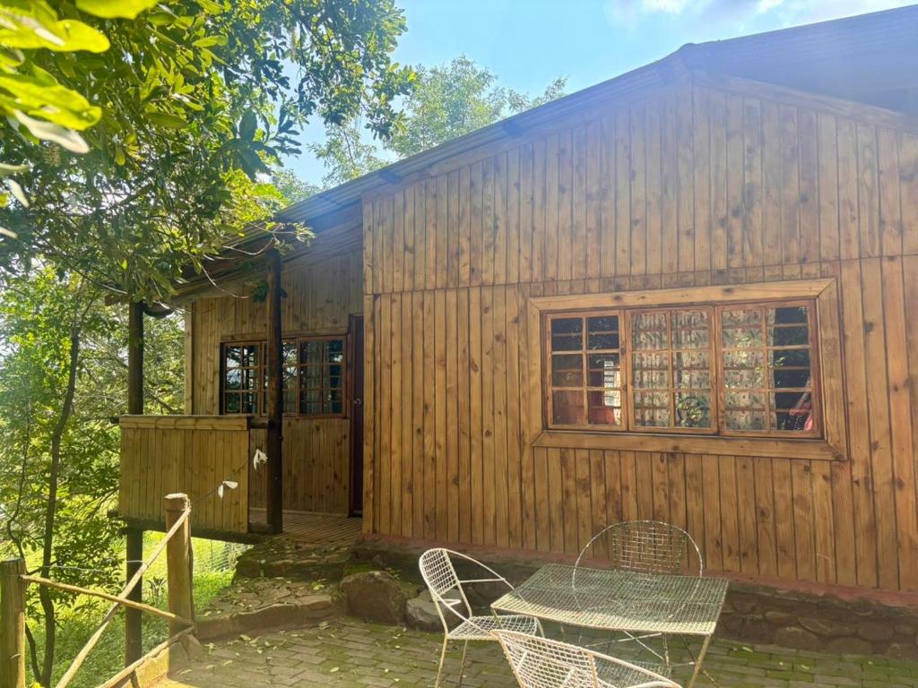 a wooden cabin with a table and chairs in front of it at Backpackers at Kanaan in Hazyview