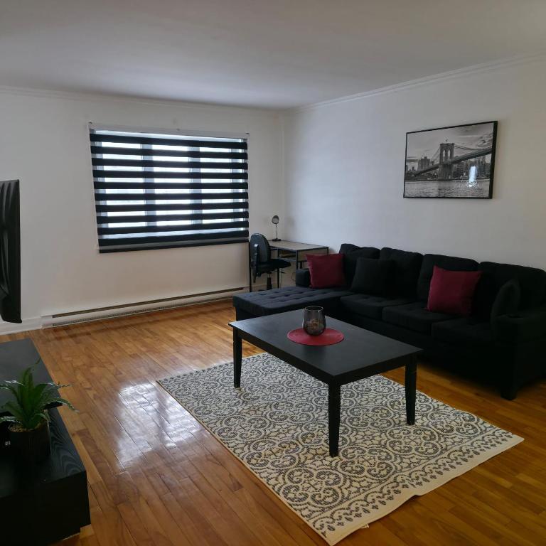 a living room with a black couch and a table at Appartement cosy, comme à la maison in Montreal