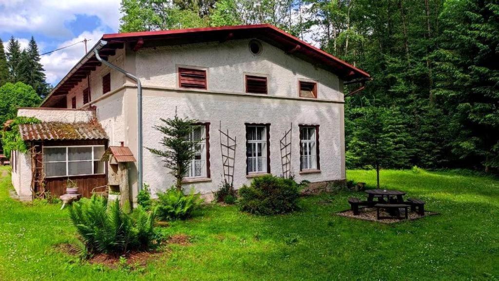 an old house in the grass with a picnic table in front at Chalupa Bonanza in Jívka