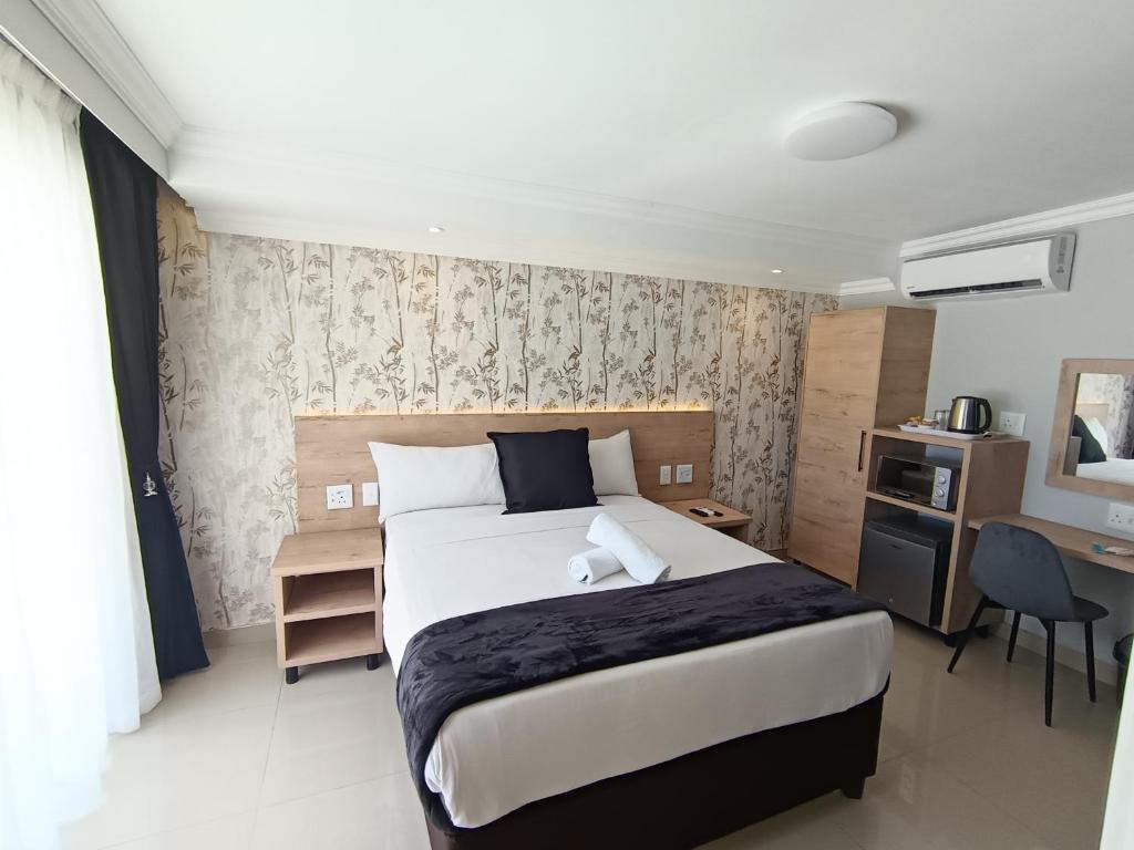 a bedroom with a large bed with a desk and a desk at Bayside Hotel Empangeni in Empangeni