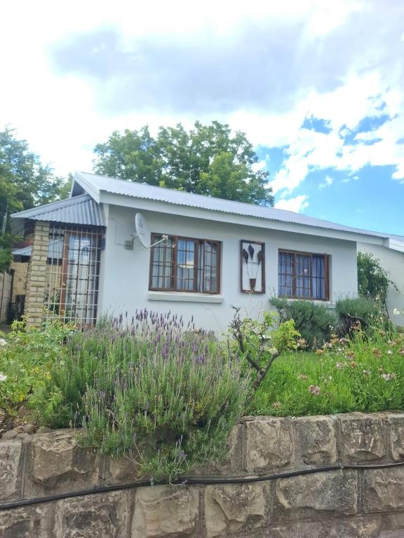 a white house with a stone wall at 33 On Loop, Flat 2 in Ladybrand
