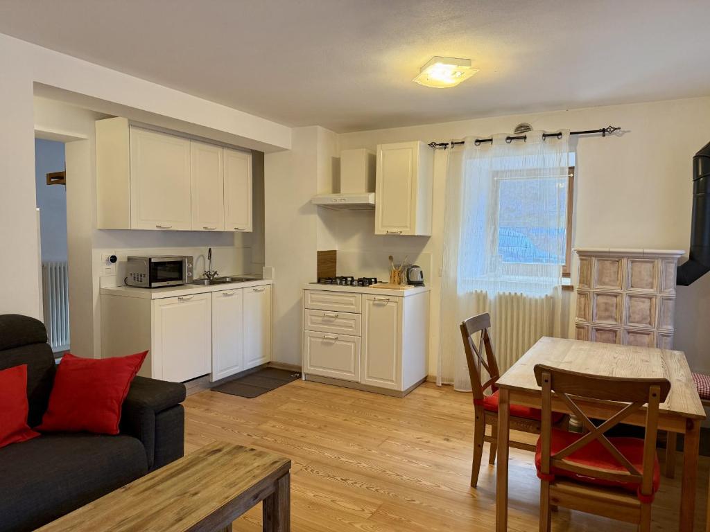 a living room with a couch and a table and a kitchen at Il Molino nel bosco - PT in Alleghe