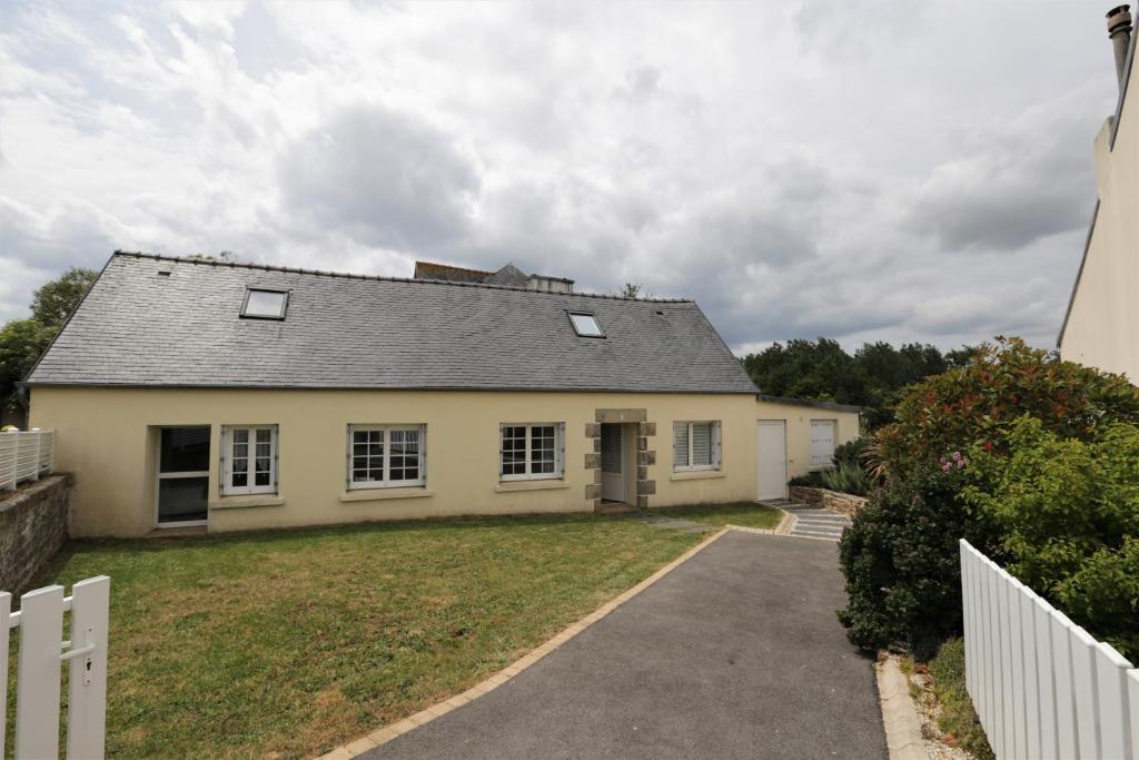 a white house with a white fence and a yard at Gite Kalon in Pouldreuzic