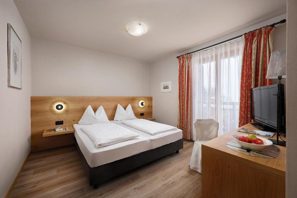 a hotel room with a bed and a television at Hotel Garni Paler in Tirolo