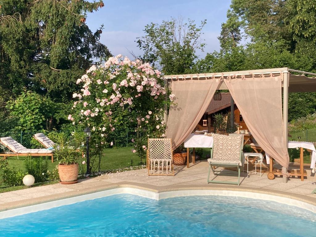 a pool with two chairs and a bush with pink flowers at Escale sur la Côte in Porrentruy