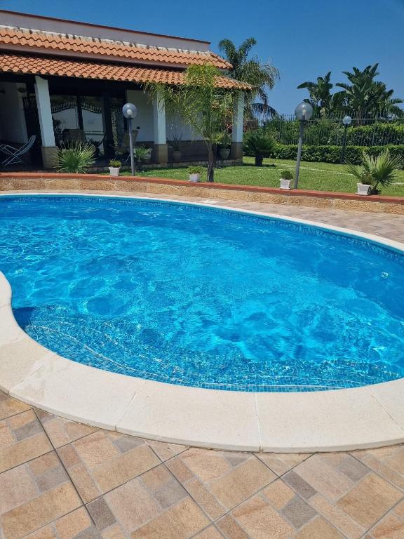 a large blue swimming pool in front of a house at Villa Sunshine in Balestrate