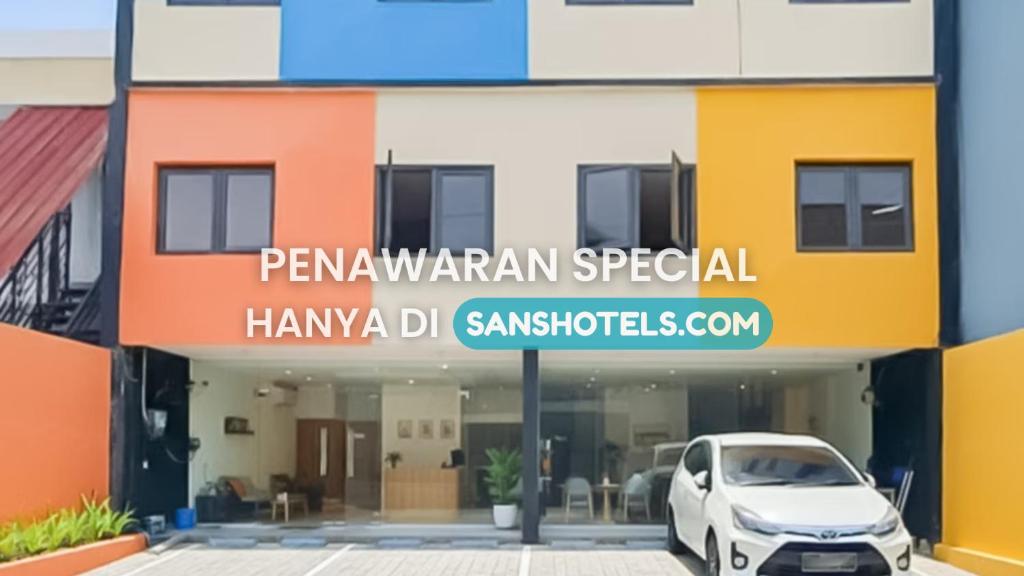 a white car parked in front of a building at SANS FYBED Hotel Semarang in Semarang