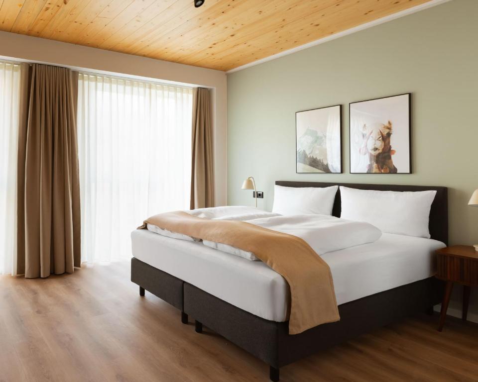 a bedroom with a large bed and a large window at Limehome Mannheim City Center in Mannheim