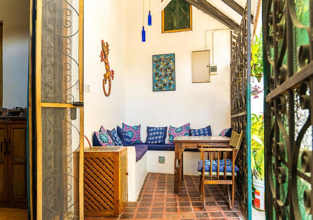 a room with a table and a bench with blue pillows at Gecko Cottage - Cosy 2-Bedroom in Bagamoyo Old Town in Bagamoyo