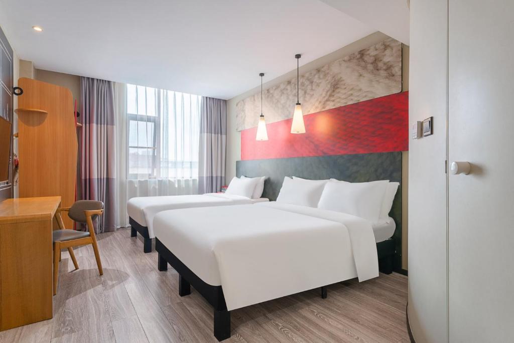 a hotel room with three beds and a desk at Ibis Chengdu Wuhouci Jinli in Chengdu