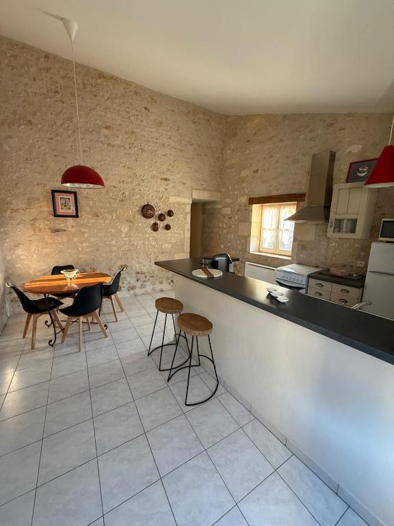 a kitchen with a counter and a table and chairs at Gîte à la campagne in Meursac