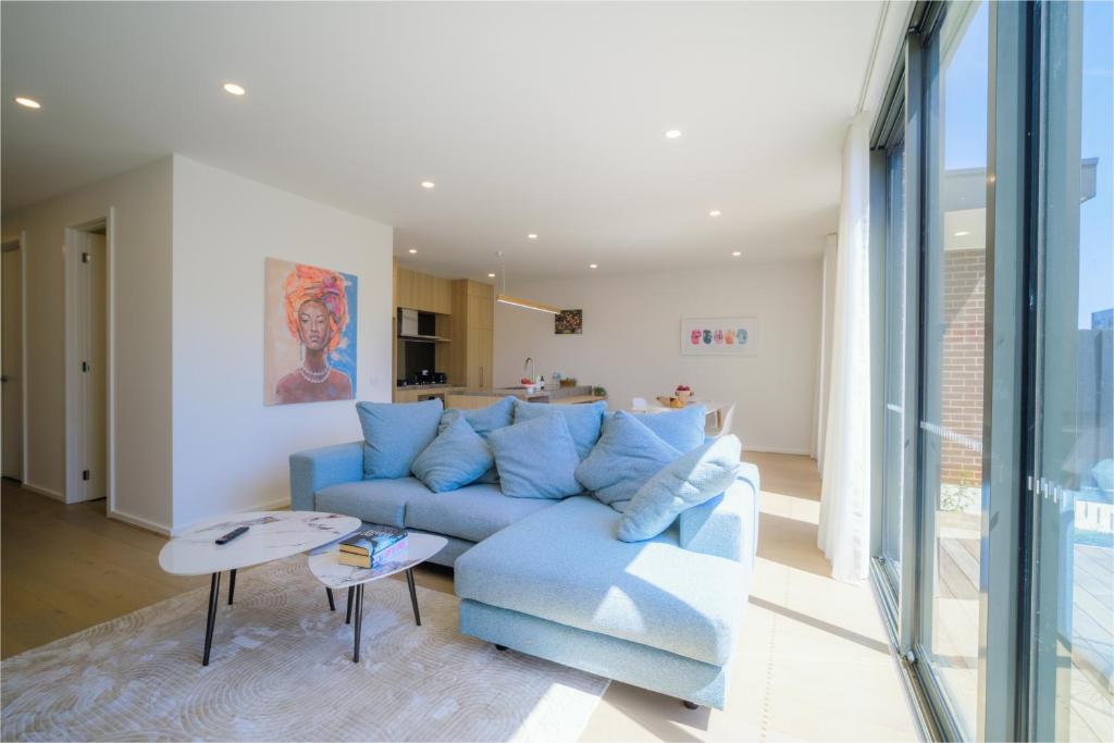 a living room with a blue couch and a table at Waverley Gardens Modern 3BR Home - Pet Friendly & Parking in Mulgrave
