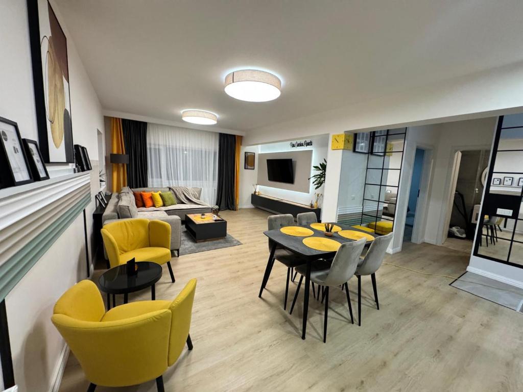 a living room with a table and yellow chairs at Ran Garden Aparts in Popeşti-Leordeni