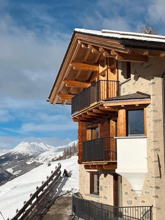 a log cabin with a balcony in the snow at Gran Zebrú B&B - high mountain in Valfurva
