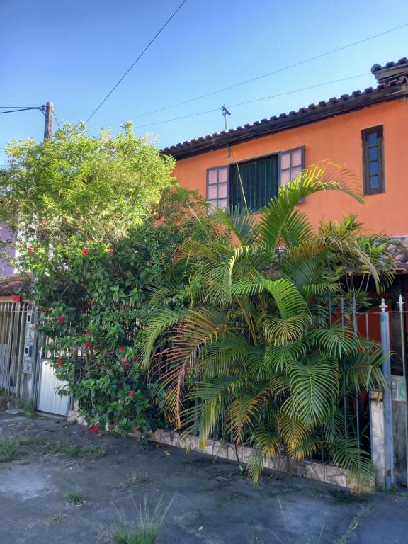 an orange house with a palm tree in front of it at Casa Completa na Praia in Saquarema