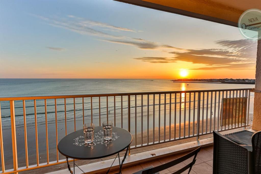 a table on a balcony with a view of the ocean at Exceptional stay facing the Atlantic Sea-view apartment with balcony in Saint-Gilles-Croix-de-Vie