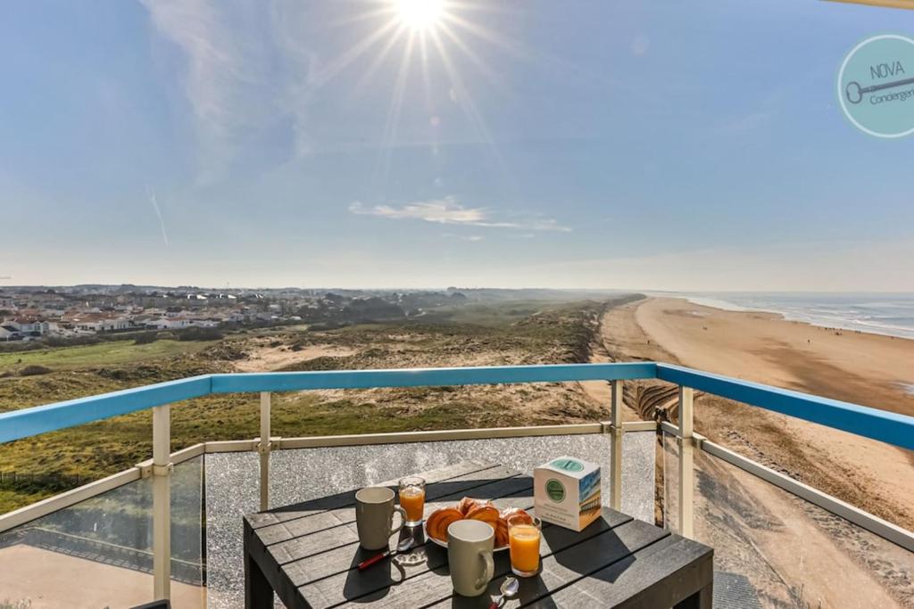 a table on a balcony with a view of the beach at Le Belvédère des Dunes in Saint-Gilles-Croix-de-Vie