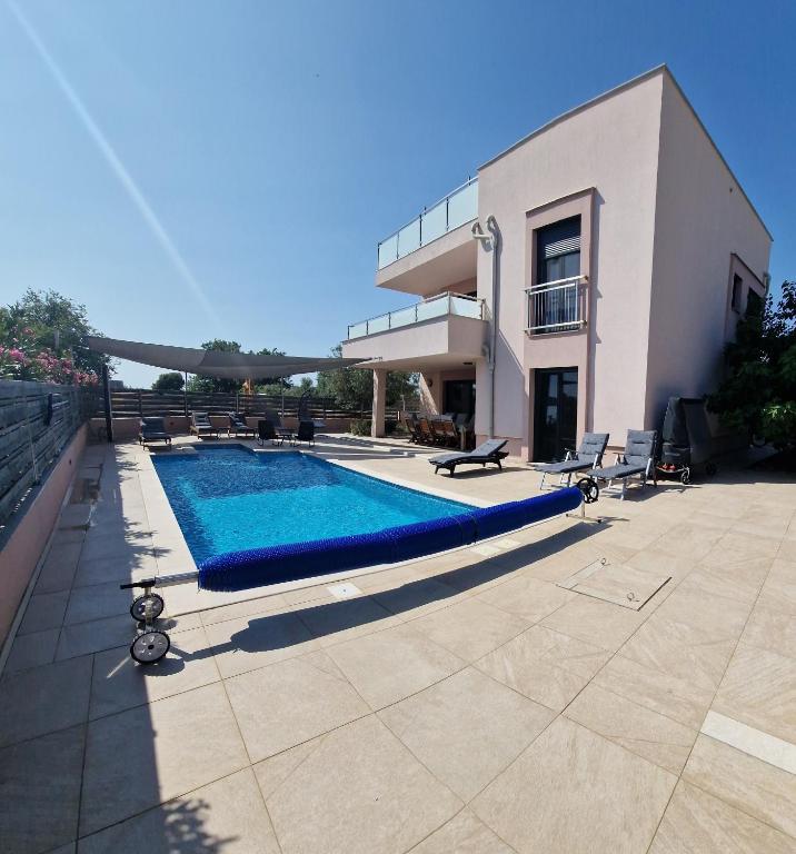 a swimming pool in front of a house at Villa Karizma - sea view, swimming pool, hot tub, Brijuni, Fazana, Peroj in Peroj