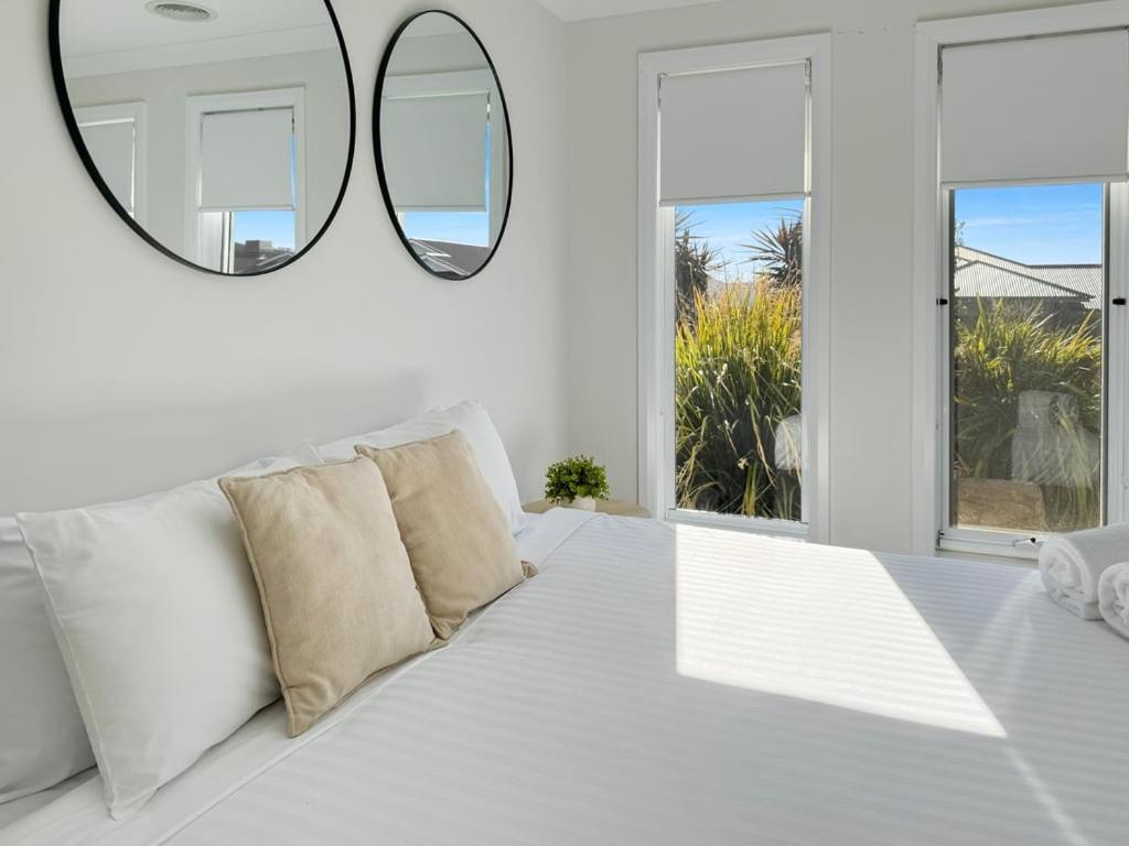 a white room with a white couch and a mirror at Paradise Stay in North Wagga