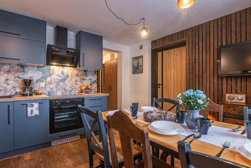 a kitchen with a wooden table and a dining room at Apartamenty Baj na Polnej - bezpłatny parking, widok na góry i zewnętrzna balia! in PyzÃ³wka