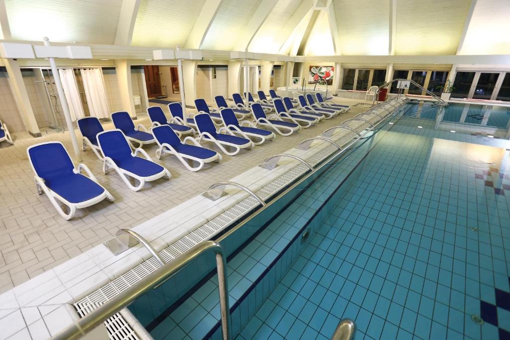 a swimming pool with blue chairs in a building at Ensana Thermal Hévíz in Hévíz