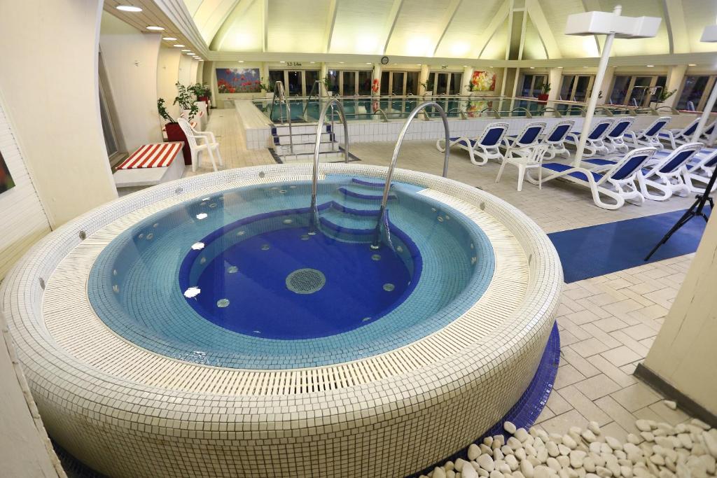 a hot tub in a building with chairs and tables at Ensana Thermal Hévíz in Hévíz
